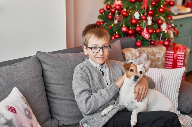 Junge mit Hund nahe Weihnachtsbaum auf Weihnachten