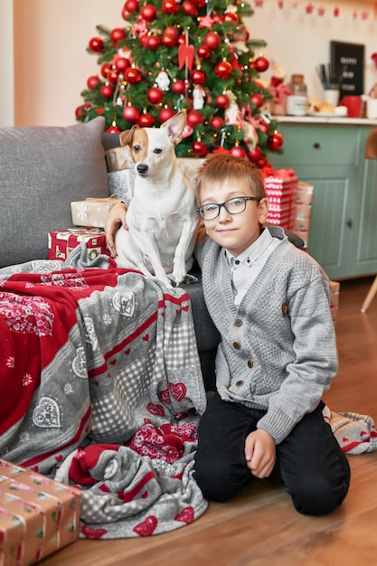 Junge mit Hund nahe Weihnachtsbaum auf Weihnachtshintergrund