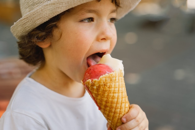 Junge mit Hut hält ein Eis und sieht glücklich und überrascht aus Sommeressen und Sommerzeit