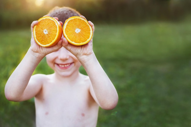 Junge mit Orangenhälften auf den Augen. glückliches Kind, das Spaß hat und lächelt.