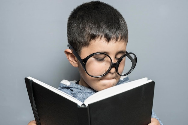 Junge mit riesiger Brille liest ein Buch mit lustigen und abwechslungsreichen Gesten