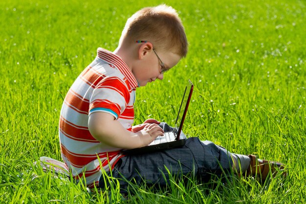 Junge mit seinem Laptop im Freien im Park auf Gras