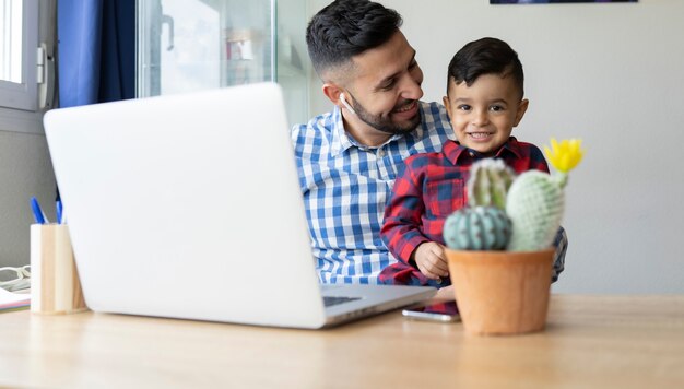 Junge mit seinem Vater am Schreibtisch mit Laptop