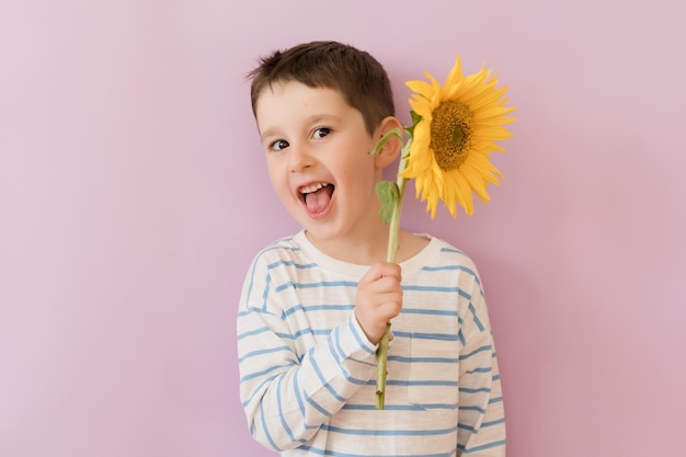 Junge mit Sonnenblume auf rosa Hintergrund