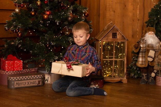 Junge mit Weihnachtsgeschenk. Netter kleiner Junge mit glücklichen Neujahrsgeschenken