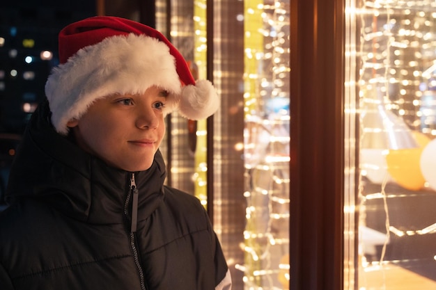 Junge mit Weihnachtsmütze schaut im Schaufenster