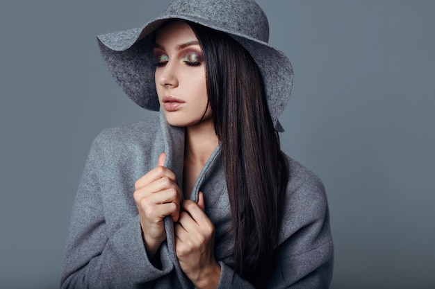Junge Mode Brunette-Frauenschönheit im grauen Mantel und im Hut