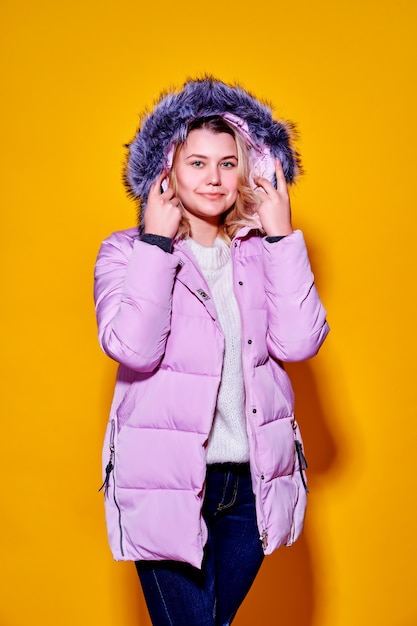 Junge Modefrau in der kurzen violetten Daunenjacke.