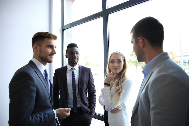 Junge moderne Kollegen in smarter Freizeitkleidung haben ein Brainstorming-Meeting, während sie im Kreativbüro stehen.