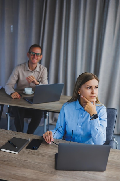 Junge müde Geschäftsfrau sitzt lange am Schreibtisch und hat das Bürosyndrom Ein harter Arbeitstag im Büro