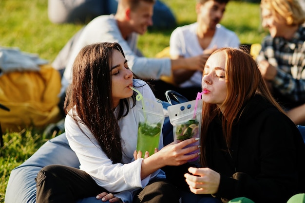 Junge multiethnische Gruppe von Menschen, die sich im Open-Air-Kino einen Film ansehen Zwei Mädchen mit Mojito-Cocktails