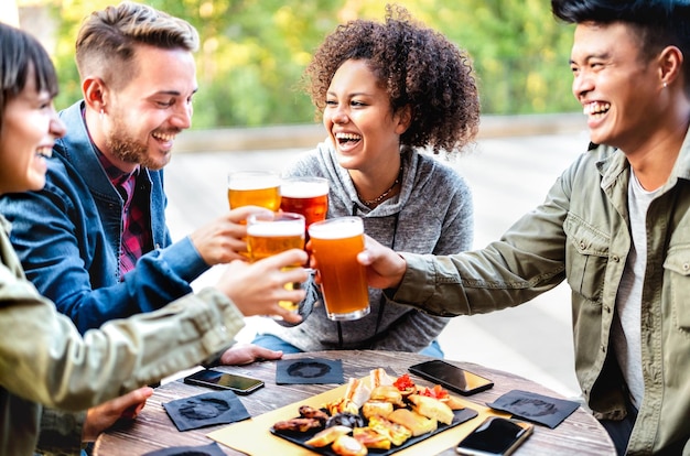 Junge multikulturelle Freunde trinken und rösten Bier auf der Terrasse der Brauereibar