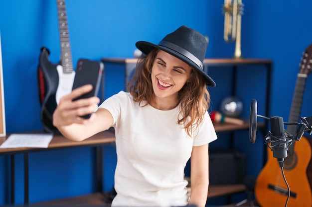 Junge Musikerin macht Selfie per Smartphone im Musikstudio