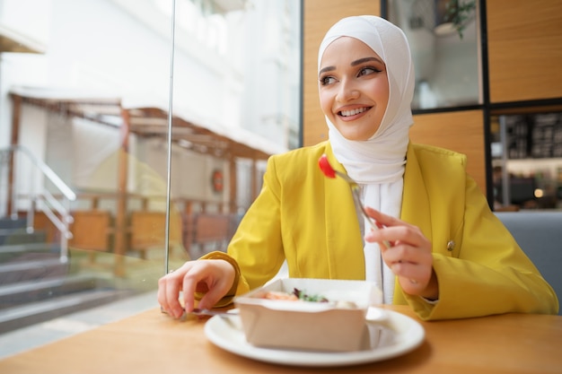 Junge muslimische Frau im Hijab beim Mittagessen im Café?