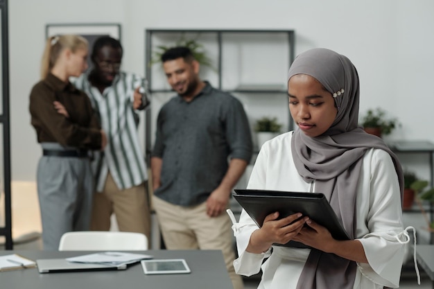 Junge muslimische Geschäftsfrau im Hijab mit schwarzem Ordner mit Dokumenten