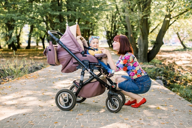 Junge Mutter, die ihr Kind in einem Kinderwagen betrachtet