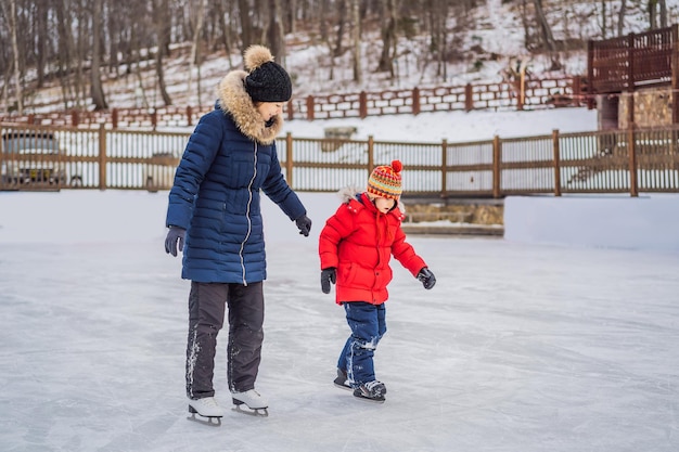 Junge Mutter, die ihrem kleinen Sohn Eislaufen auf der Eisbahn im Freien beibringt Familie genießt den Winter auf der Eisbahn im Freien