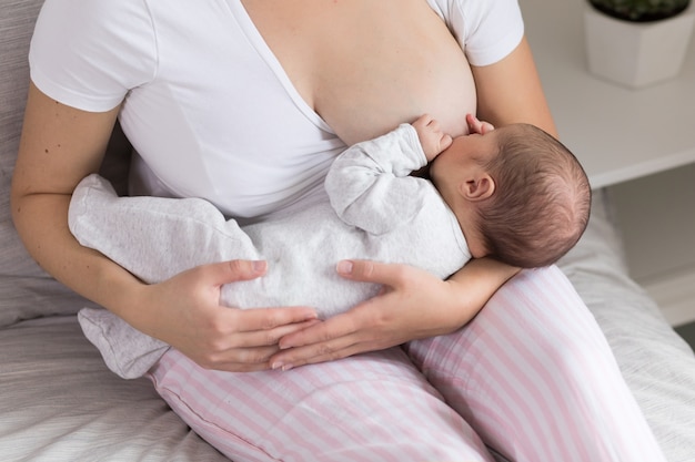 Junge Mutter, die ihren neugeborenen Babysohn stillt