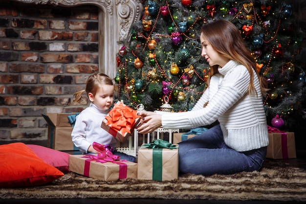 Junge Mutter, die ihrer kleinen Tochter ein Weihnachtsgeschenk gibt