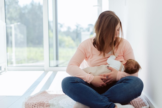 Junge Mutter, die zu Hause neugeborenes Baby stillt