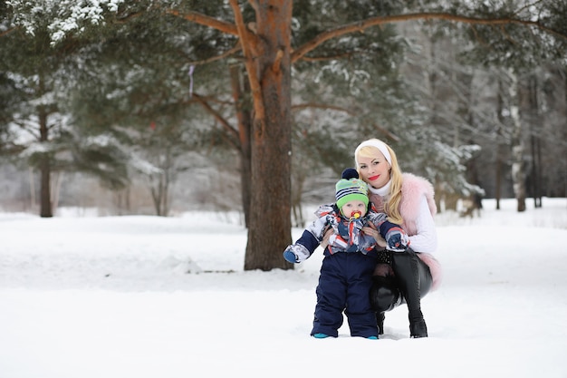 Junge Mutter geht an einem Wintertag mit einem Baby im Arm im Park
