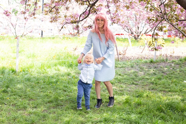 Junge Mutter geht im Frühling mit einem kleinen Sohn im Park spazieren