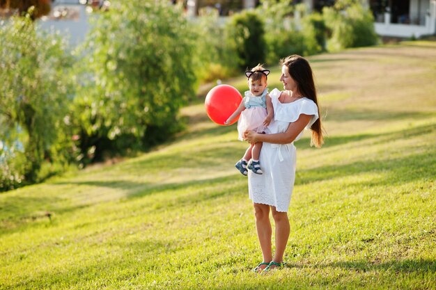 Junge Mutter hält an Händen Babymädchen mit Ballon im Türkei-Resort