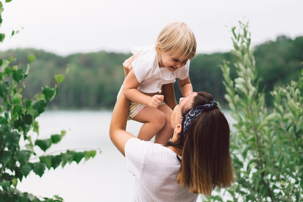 Junge Mutter hält ihr Baby. Mutter und kleine Tochter haben eine gute Zeit in der Natur.