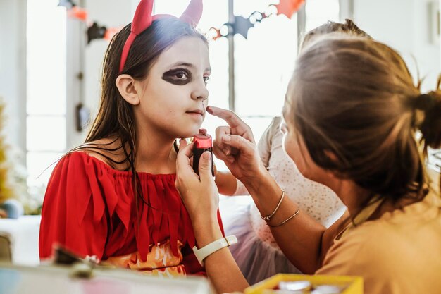 Foto junge mutter macht halloween-make-up für ihre töchter