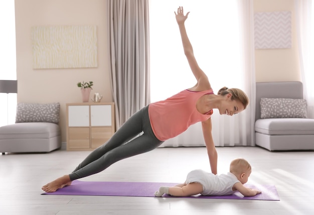 Junge Mutter macht Yoga mit Baby zu Hause