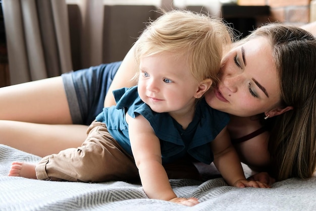 Junge Mutter mit einem kleinen Kind liegt auf dem Bett und umarmt ein qualitativ hochwertiges Foto