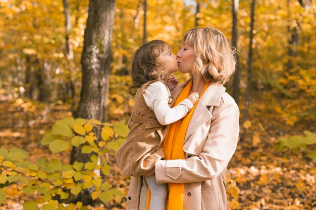 Junge Mutter mit ihrer kleinen Tochter in einem Herbstpark. Herbstsaison, Elternschaft und Kinderkonzept.