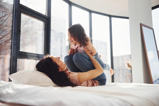 Junge Mutter mit ihrer Tochter am Wochenende gemeinsam im Bett Spaß haben