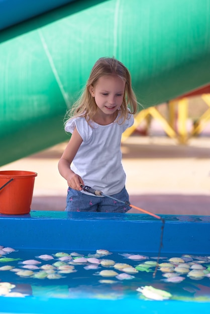 Junge Mutter mit ihrer Tochter kühlt sich bei heißem Wetter vor den Toren der Klimaanlage im Wasserpark ab. Aerosolversprühen von Wasserstrahlen, Versprühen von Kühlwasser, Klimaanlagendüse