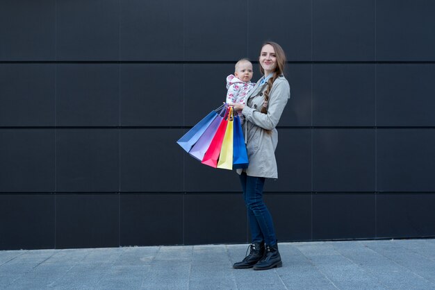 Junge Mutter mit kleiner Tochter und Einkaufstüten