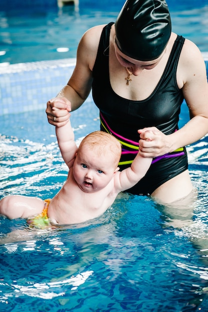 Junge Mutter, Schwimmlehrerin und glückliches kleines Mädchen im Planschbecken