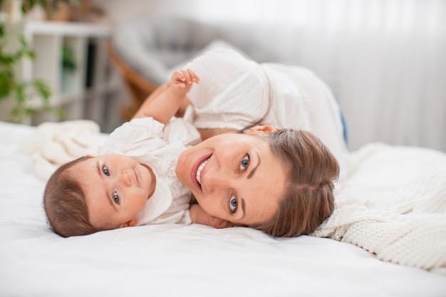 Junge Mutter spielt mit ihrem Kind im Schlafzimmer