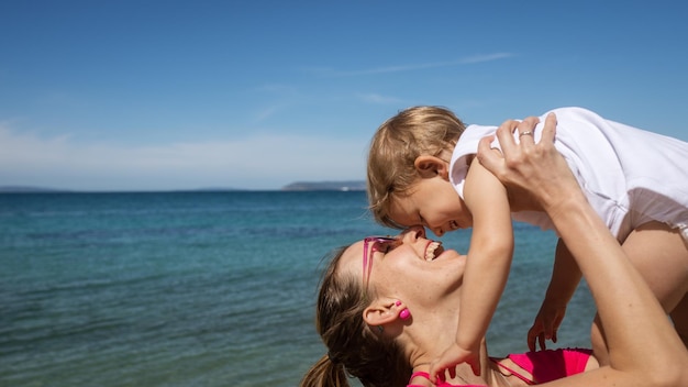 Junge Mutter spielt mit ihrer Tochter am Meer