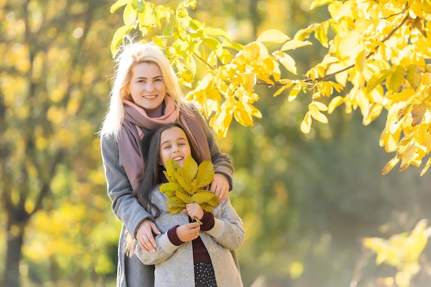 Junge Mutter spielt mit ihrer Tochter im Herbstpark.