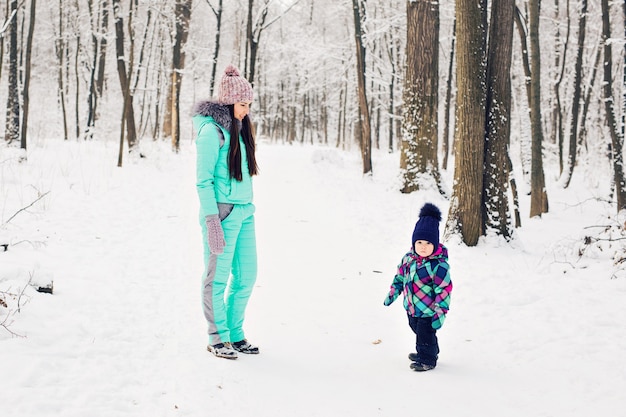 Junge Mutter und ihre kleine Tochter genießen einen schönen Wintertag im Freien.