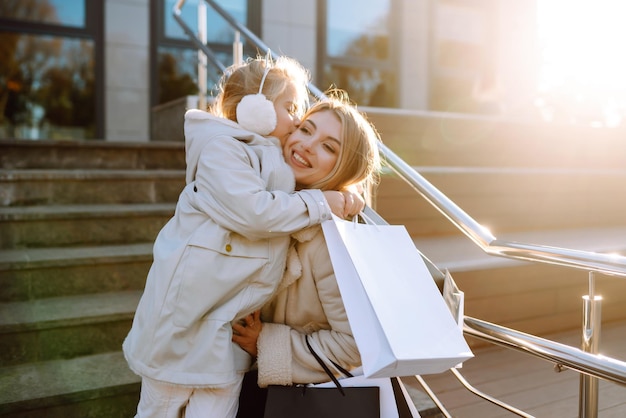Junge Mutter und kleines Mädchen mit Einkaufstüten nach dem Einkaufen Frühlingsstil-Konsumismus