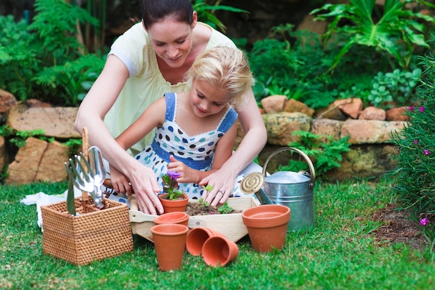 Junge Mutter und Tochter, die Blumen pflanzt