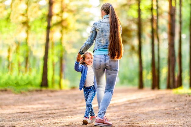 Junge Mutter und Tochter, die Spaß im Wald haben Sonniger Sommertag Verspielte Stimmung