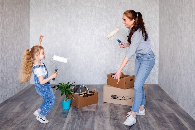 Junge mutter und tochter tanzen und spielen mit farbrollern herum.