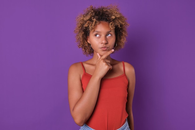 Junge nachdenkliche afroamerikanische Frau, Teenager, die das Kinn berührt, steht im Studio