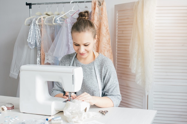 Junge Näherin, die an Nähmaschine arbeitet