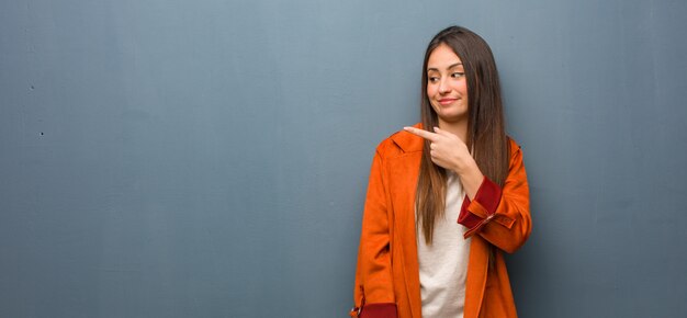 Junge natürliche Frau, die auf die Seite lächelt und zeigt