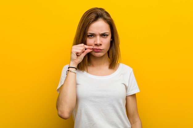 Junge natürliche kaukasische Frau mit den Fingern auf den Lippen, die ein Geheimnis halten.