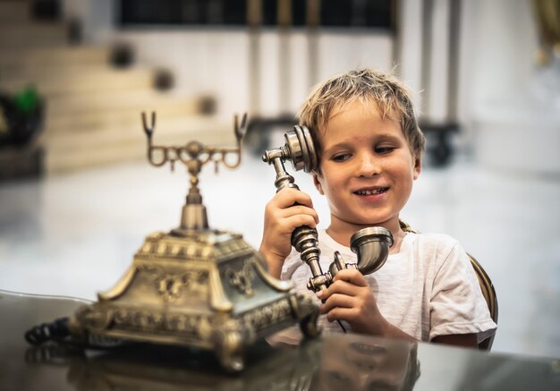 Junge nehmen Telefonhörer spielen mit antiken Vintage rotierenden alten Festnetztelefon auflegen schön geprägte Goldbronze Textur Retro-Stil Konzept des Reichtums Wohlstand Schönheit der Kunst des letzten Jahrhunderts