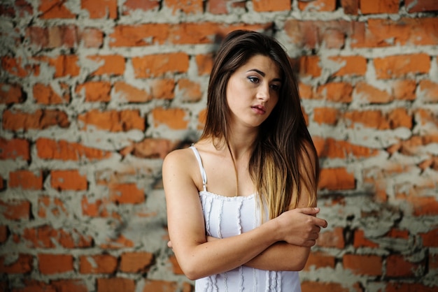 Junge nette Brunettemädchen-Hintergrundbacksteinmauer.